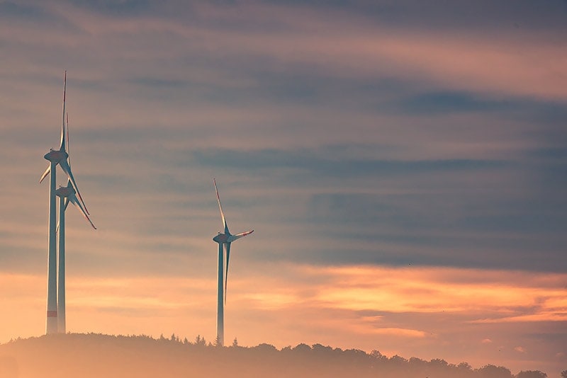 Landschaft mit drei Windrändern bei Sonnenuntergang